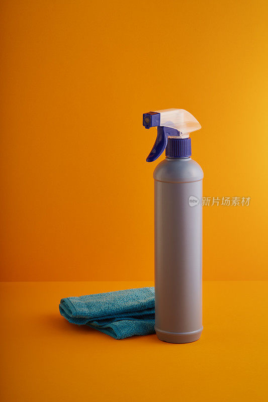 喷上清洁产品瓶和清洁布，以黄色/橙色为背景